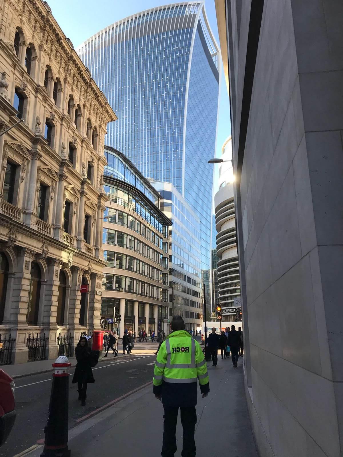 岩石电源连接的一名员工穿着一件夹克，抬头看着伦敦的一座摩天大楼